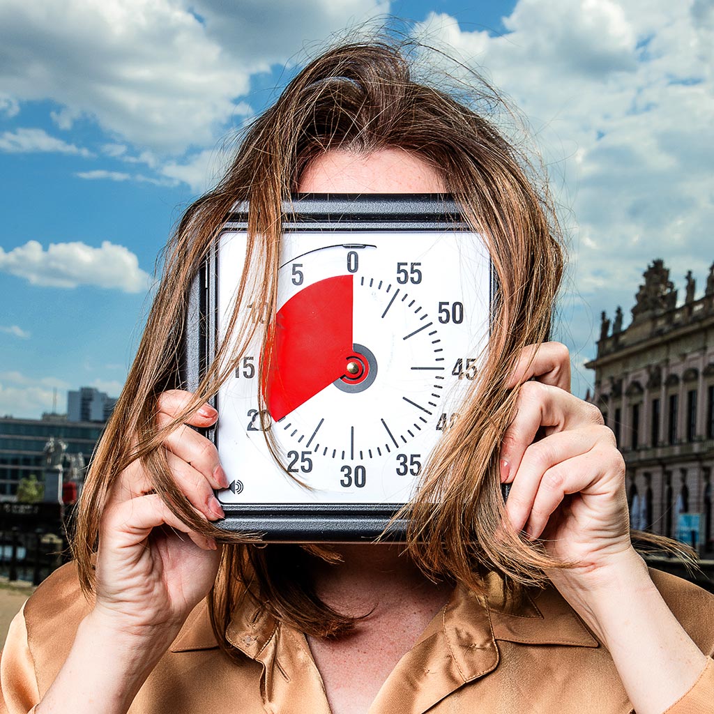Woman holding big clock in front of her face